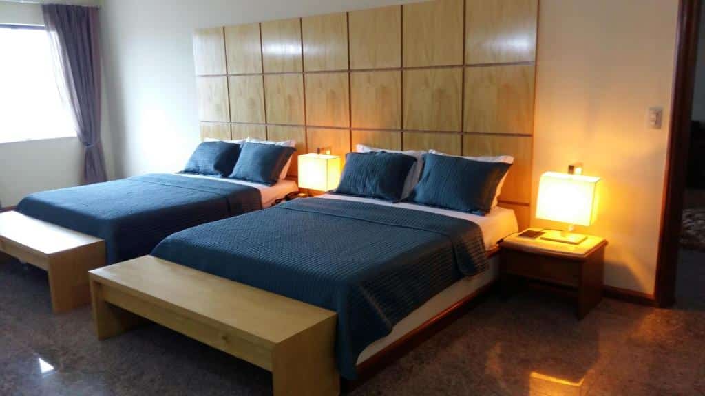 Quarto com duas camas, recamier no pé de cada uma, abajures ao lado e uma janela com cortina. Foto para ilustrar post de hotéis em Belém do Pará.