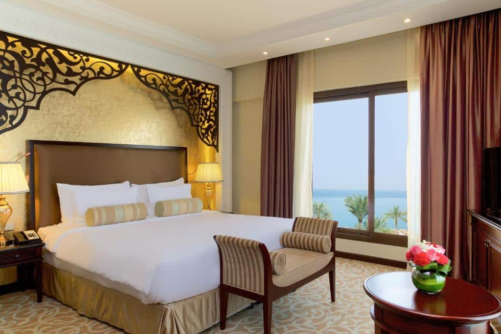 Quarto do Marjan Island Resort & Spa Managed By Accor com uma janela com vista para o mar, uma cama de casal, com uma cabeceira desenhada, um pequeno sofá e uma televisão