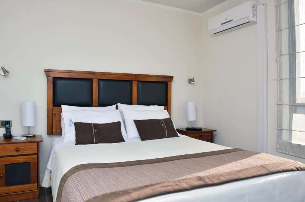 Quarto do Norus Apartments Providencia com cama de casal, duas cômodas ao lado da cama com luminária.