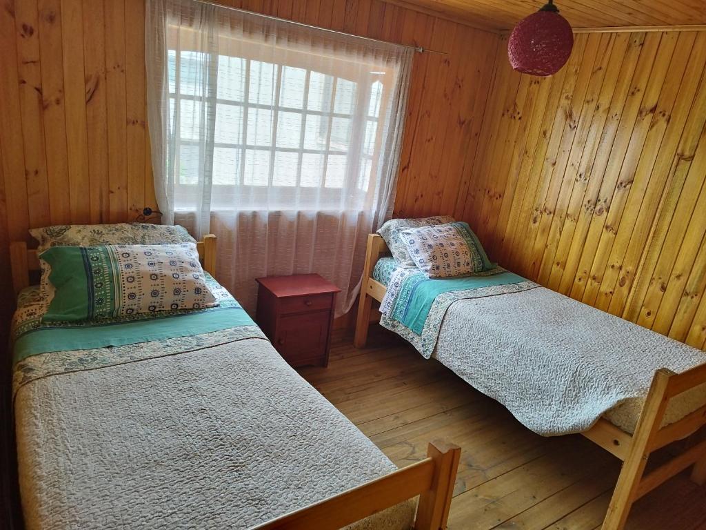 Quarto do Hostal Sol y Luna com duas camas de casal e uma cômoda no meio.