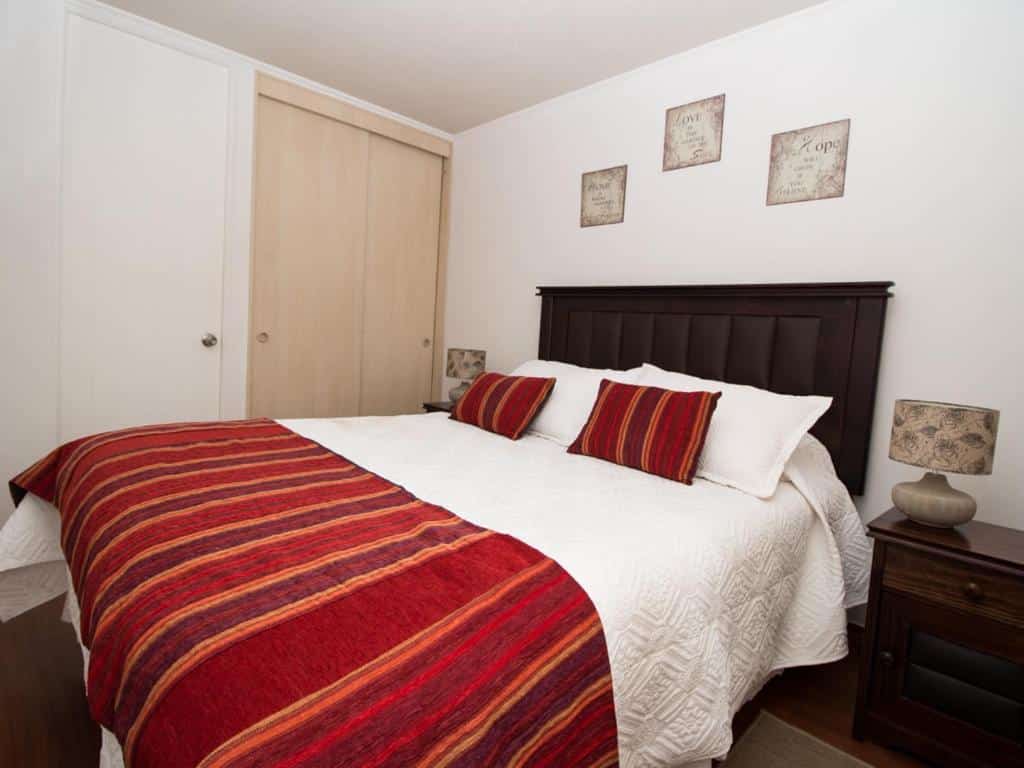 Quarto do Sweet Stay Chile com cama de casal e ao lado duas cômodas de madeiras.