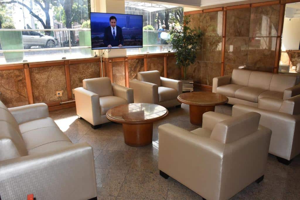 Área de recepção com vários sofás, uma televisão e janelas de vidro mostrando a rua. Imagem para ilustrar post de hotéis em Belém do Pará.