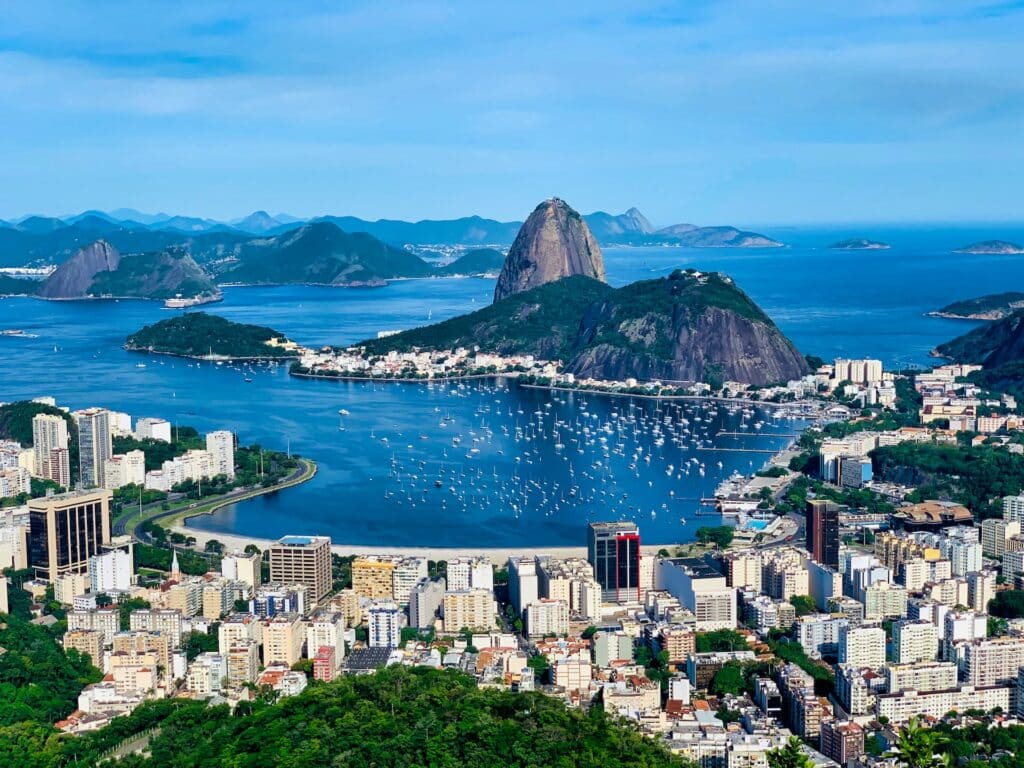 Imagem de uma ilhota perto dos prédios da cidade e vários barcos na água azul durante o dia, ilustrando post hotéis Ibis no Rio de Janeiro.
