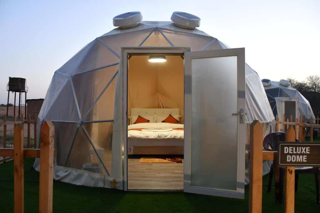 Uma espécie de cúpula transparente no The Dunes Camping & Safari RAK com um quarto dentro com cama e outros móveis