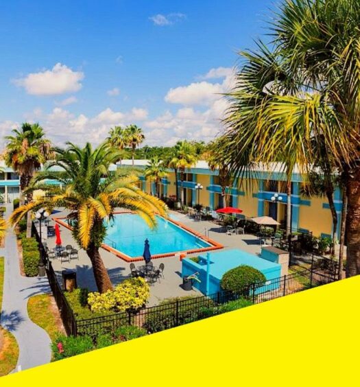 vista do Bposhtels Orlando Florida Mall um hostel em Orlando, com piscina retangular com palmeiras ao redor e céu azul com nuvens
