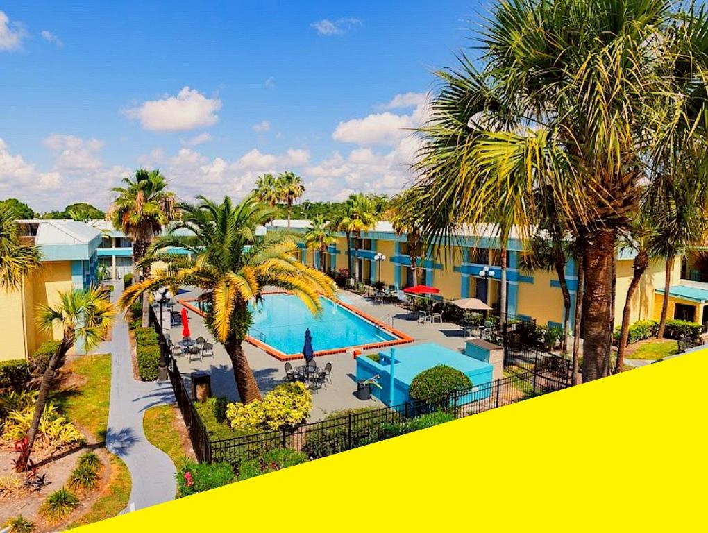 vista do Bposhtels Orlando Florida Mall um hostel em Orlando, com piscina retangular com palmeiras ao redor e céu azul com nuvens