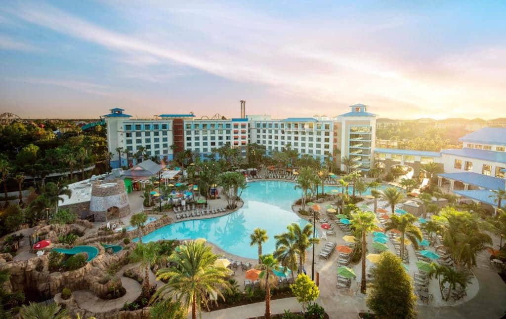 vista de uma grande fachada com várias janelinhas em tons de azul com palmeiras e uma piscina enorme em forma de lagoa no Universal's Loews Sapphire Falls Resort, um dos hotéis da Universal em Orlando