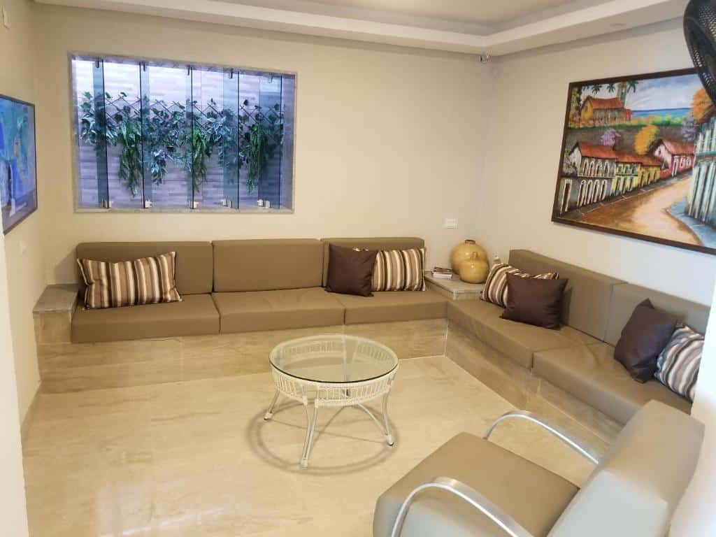 Uma poltrona, e sofás na parede, com uma mesa de centro e uma televisão no canto esquerdo na parede. Foto para ilustrar post sobre hotéis perto do Consulado Americano em Recife.
