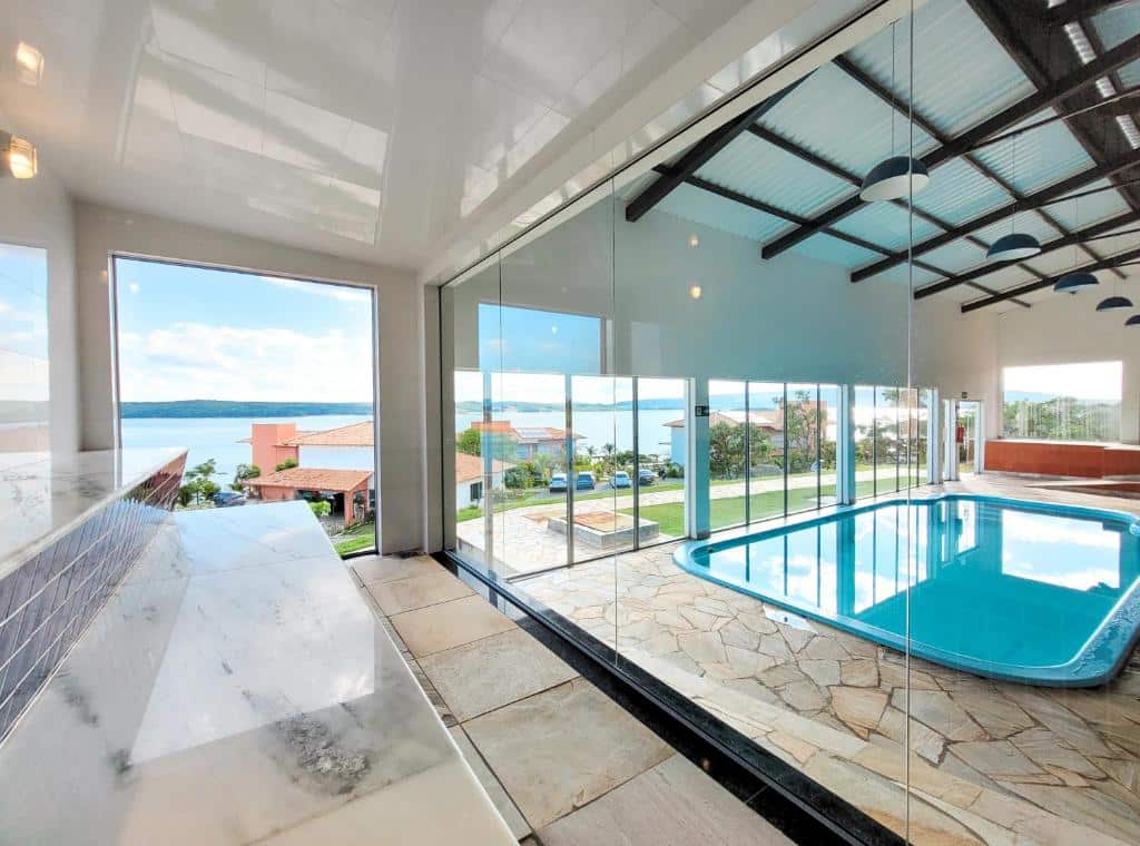 Imagem da piscina interior do Riviera Capitólio Hotel. A piscina interna é em área coberta, com aquecimento e há janelas de vidro ao seu redor.