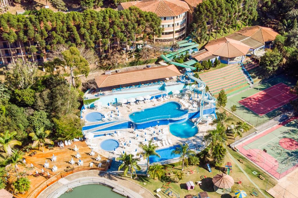 Vista aérea do Vilage Inn All Inclusive em Poço de Caldas, em Minas Gerais. Vemos diversas piscinas com escorregadores aquáticos, quadras de esporte, mesas com guarda-sol e espreguiçadeiras e um parque infantil. A foto representa o post sobre hotéis com piscina aquecida em Minas Gerais.