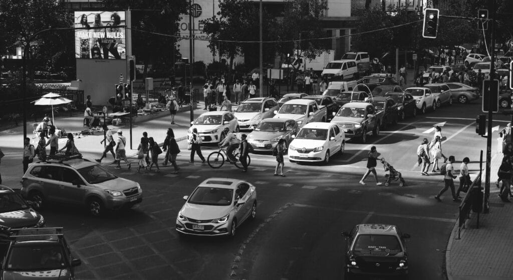 Transito em Santiago, durante o dia com carros e pessoas andando. Representa aluguel de carros no aeroporto em Santiago.