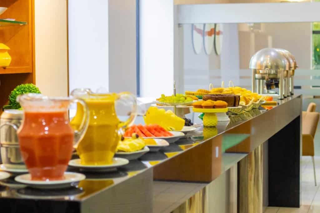 Bancada de hotel em Teresina com café da manhã. Frutas, bolos e jarros de suco.