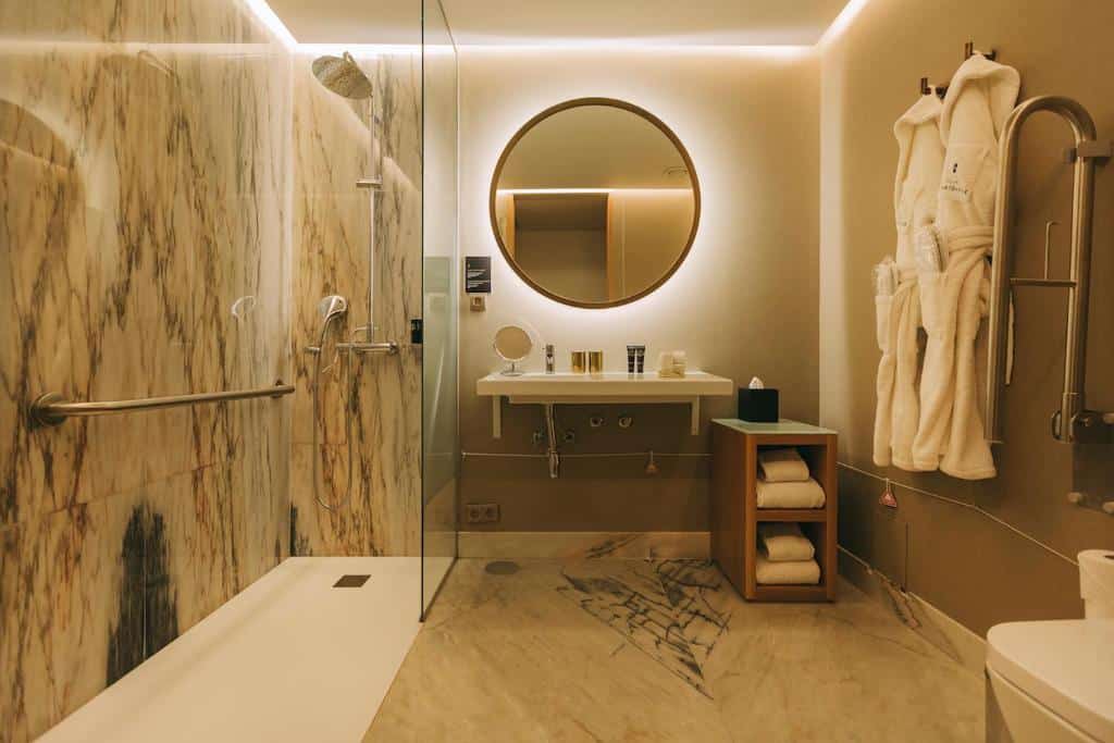 Banheiro com acessibilidade do Torel Avantgarde ambiente amplo com barras de apoio e piso plano. Representa hotéis para lua de mel em Portugal.