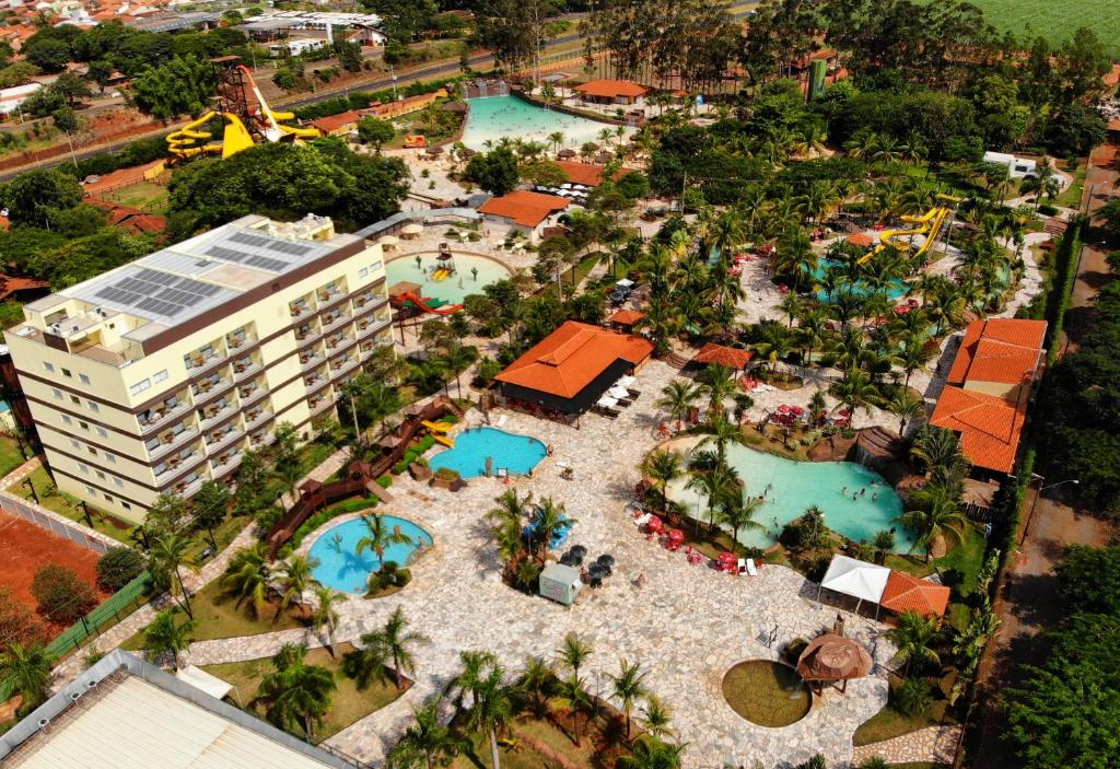 Vista aérea do resort com várias piscinas, um prédio e muitas árvores verdes, ilustrando post Hotéis em Barretos.