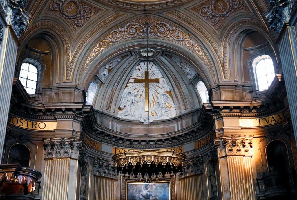 interior da Basílica de Santo Eustáquio, em Roma, com uma grande cruz dourada no centro, e detalhes todos em dourado, ricamente trabalhados e com ornamentos por todos os lados