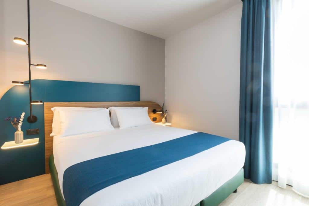 Quarto do Belstay Milano Linate  com uma cama de casal, uma cabeceira com luminária, tudo em detalhes de azul com branco