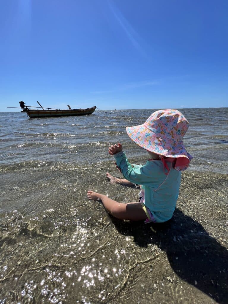 criança de costas brincando no mar na maré baixa