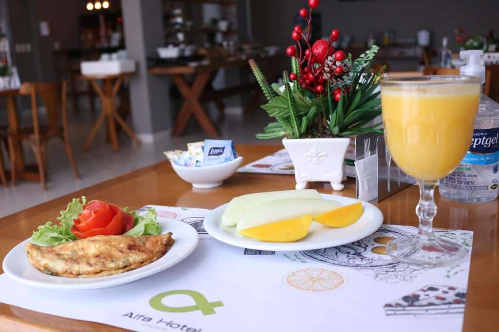 Café da manhã em mesa de hotel com pratos com omelete, frutas e copo de suco.