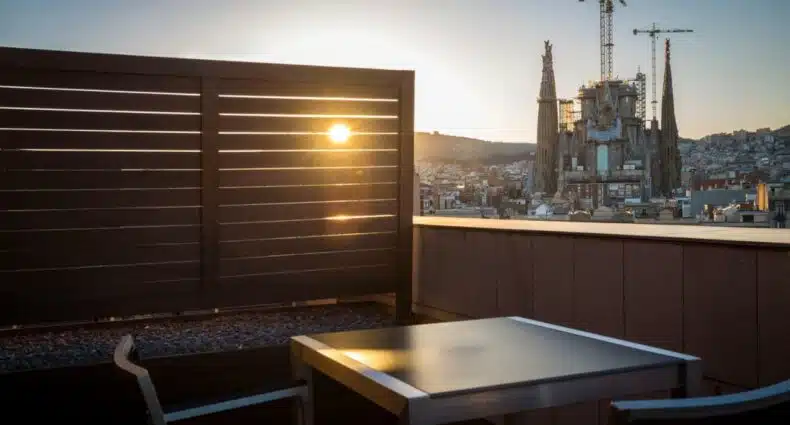 Vista do terraço de um quarto do Eurostars Monumental, uma das recomendações de hotéis perto da Sagrada Família em Barcelona. A igreja da Sagrada Família pode ser vista ao fundo com o sol se pondo logo ao lado.