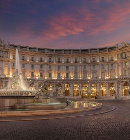 fachada do Anantara Palazzo Naiadi Rome Hotel, um dos hotéis de luxo em Roma, com luzes e uma fonte na frente