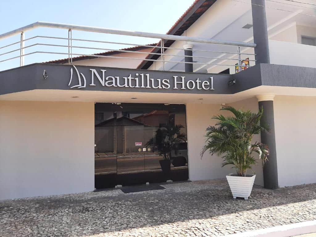 Fachada do Nautillus Hotel em Parnaíba. Porta de vidro escura, planta ao lado da entrada e é possível ver o segundo andar da propriedade.
