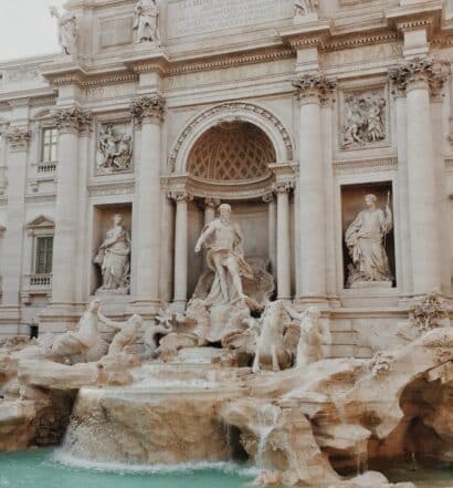 vista da fachada com colunas gregas da Fontana Di Trevi, em Roma, com águas claras e esculturas de Netuno ricamente trabalhadas em estilo clássico em branco