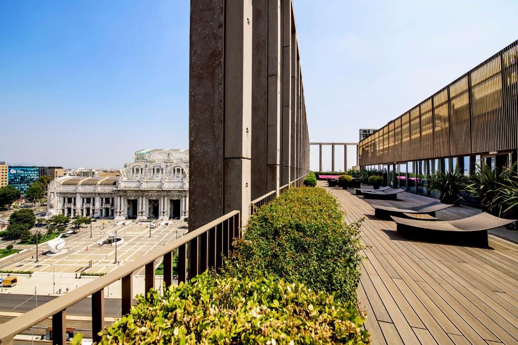 Varanda no terraço superior do Glam Milano com algumas espreguiçadeiras e arbustos, do local é possível avistar a estação, para representar hotéis perto da Estação Central em Milão