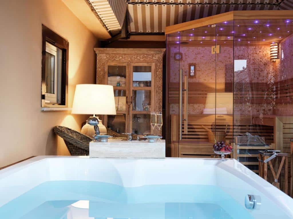 banheira de hidro no Hotel Barocco com mesa com cadeiras e um ambiente de sauna bem iluminado