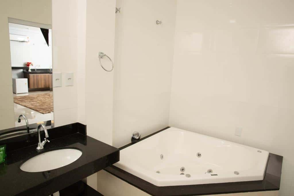 Banheiro do Hotel Araguaia com banheira de hidromassagem, espelho e pia.