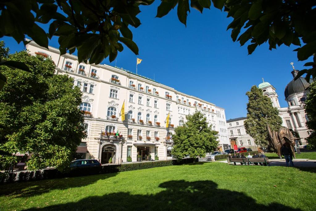 Fachada do hotel em frente a gramado verde e algumas árvores ao redor durante o dia, ilustrando post Hotéis em Salzburg.