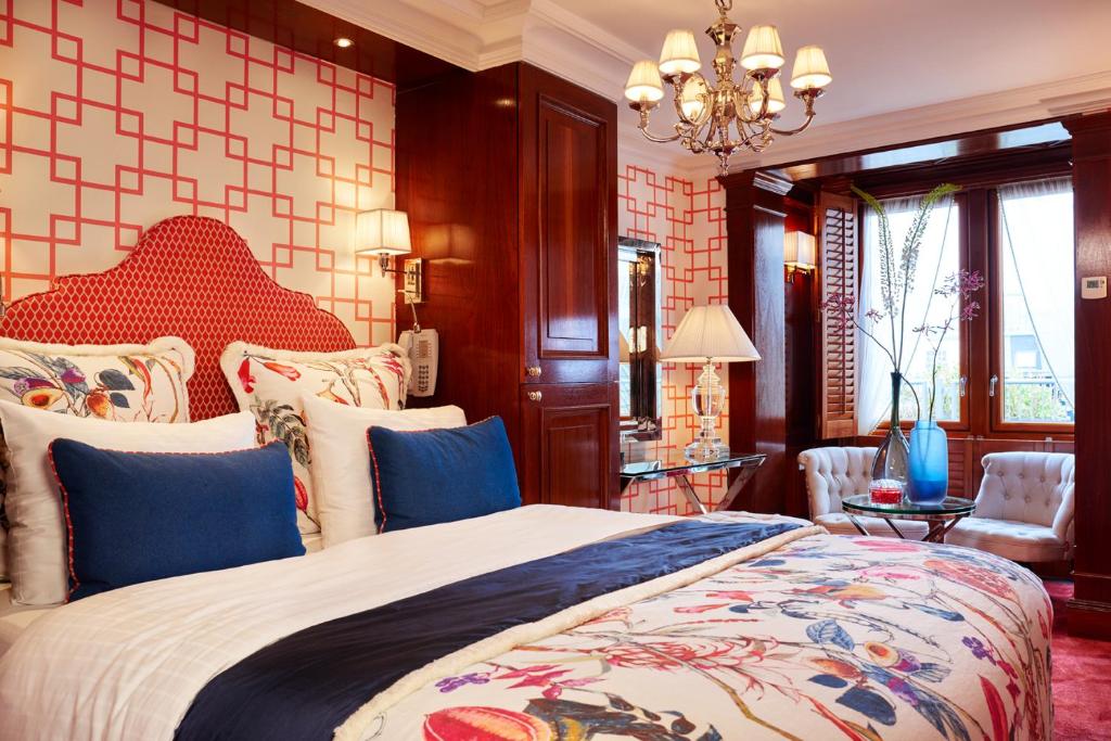 Quarto do Hotel Estheréa, com uma cama de casal com almodafas em cima e, ao fundo uma mesa redonda com duas poltronas estofadas ao lado. Imagem para ilustrar o post de hotéis românticos em Amsterdam