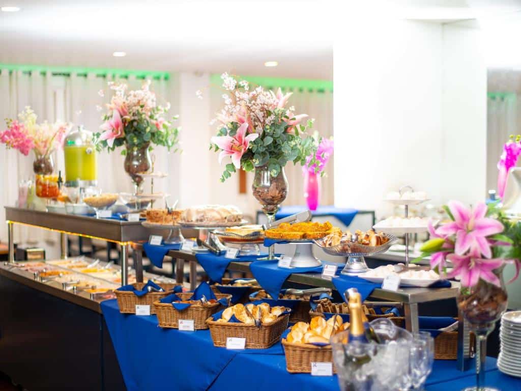 Mesa do café da manhã com várias comidas e alguns vasos de flor, ilustrando post Hotéis perto da 25 de Março em SP.