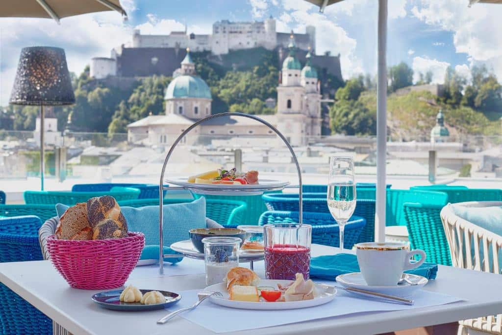 Café da manhã exposto na mesa com vista para a paisagem da cidade durante o dia, ilustrando post Hotéis em Salzburg.