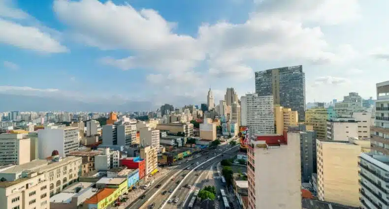 Vários prédios altos no centro da cidade e avenidas movimentadas com carros durante o dia, ilustrando post hotéis perto da 25 de março em sp.