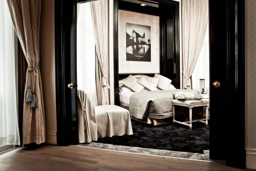 Quarto Champagne Suite Balcony do InterContinental Amstel Amsterdam, de 54 m², com cama de casal, poltronas e um tapete felpudo preto em baixo da cama. Imagem para ilustrar o post de hotéis românticos em Amsterdam