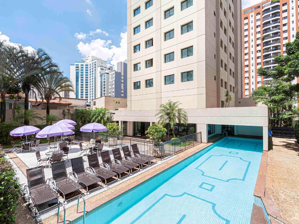 Parte de fora do hotel com piscina azul, algumas cadeiras para sentar na beira da piscina e alguma mesas com guarda-sol, ilustrando post Hotéis Mercure em São Paulo.