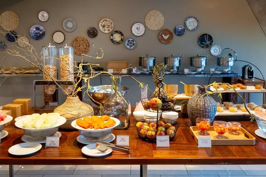 Mesa de café da manhã de hotel luxuoso em Teresina com decorações de plantas, frutas, cereais e outra mesa com outros alimentos vista ao fundo.