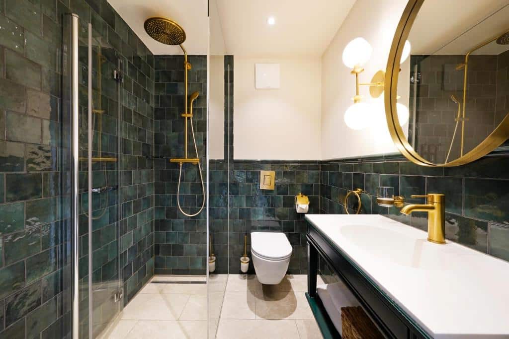 Banheiro do hotel com azulejos pretos e paredes brancas, com detalhes dos objetos em dourado, ilustrando post Hotéis em Salzburg.
