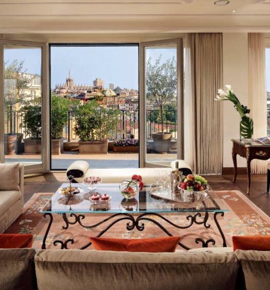 Sala de estar do Palazzo Parigi Hotel & Grand Spa - LHW com uma ampla sacada na frente com vista para a cidade, para representar hotéis de luxo em Milão