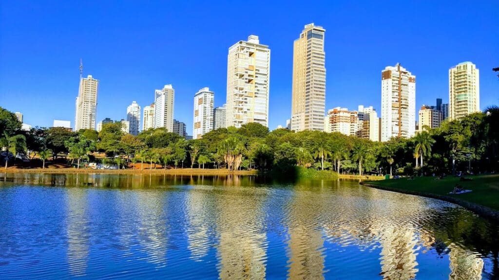 Parque Vaca Brava em Goiânia visto por um lago com árvores e prédios atrás do mesmo. Imagem para ilustrar o post hotéis em Goiânia.