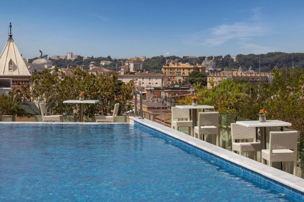 piscina com vista da cidade no Anantara Palazzo Naiadi Rome Hotel com cadeiras e mesinhas no terraço