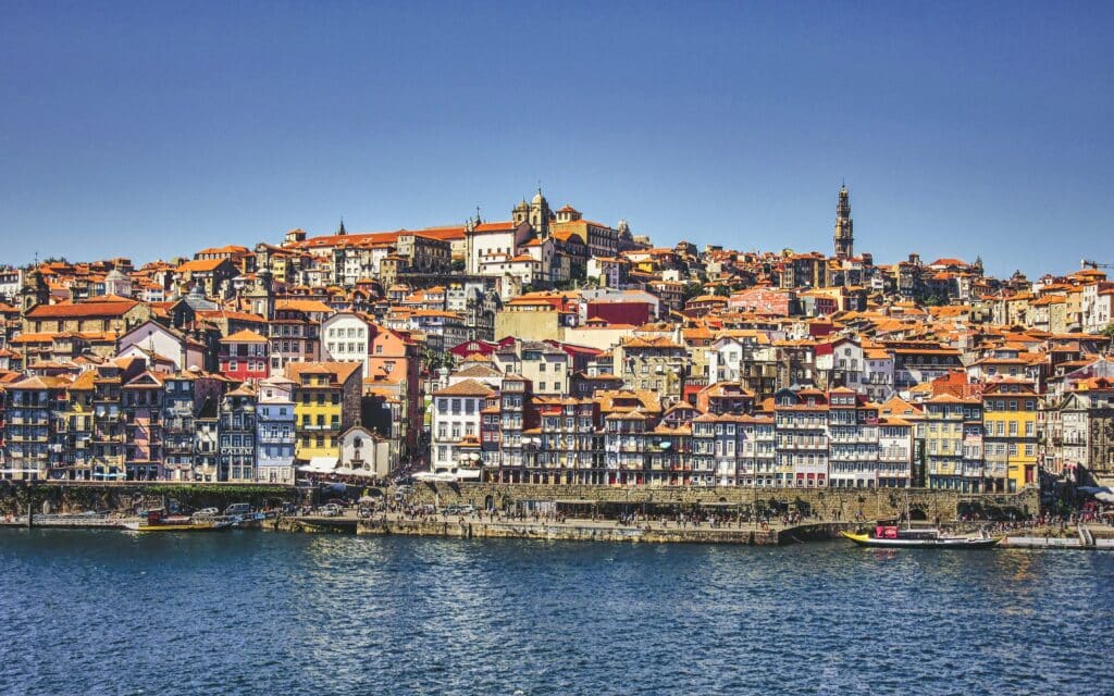 Vista do Porto, Portugal durante o dia, com o rio Douro a frente e casinhas coloridas ao fundo.