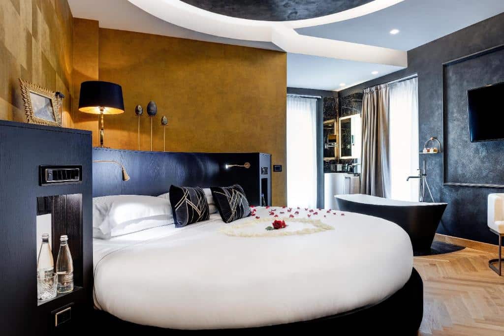 quarto do Dharma Boutique Hotel & SPA, um dos hotéis boutique em Roma, a cama é redonda e há almofadas, com luminárias acima e uma banheira de hidro do outro lado, há frigobar e tudo está em tons pretos e dourados
