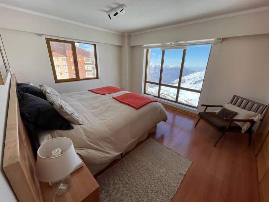 Quarto do Departamento Valle Nevado, Ski in – Ski out com cama de casal dolado esquerdo em frente a cama janela ampla com vista para as montanhas.