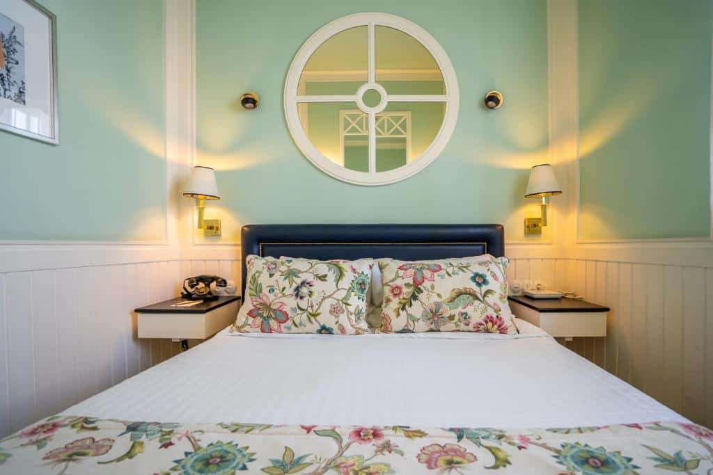 Quarto do Grande Hotel do Porto com cama de casal no centro do quarto e duas cômodas ao lado da cama. Representa hotéis de luxo no Porto.