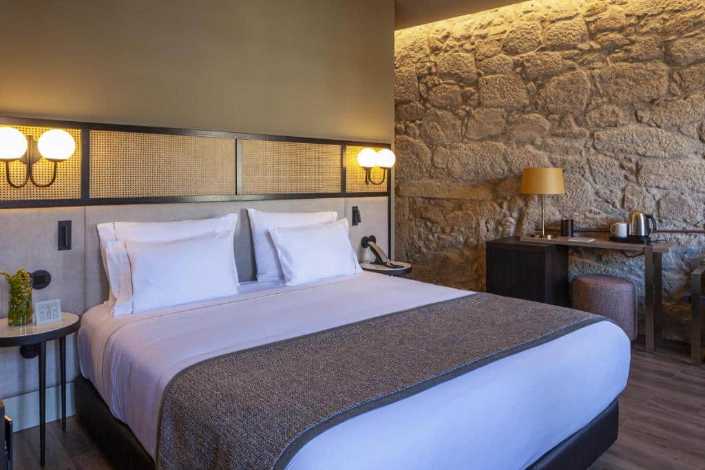 Quarto do Hotel das Virtudes com cama de casal do lado esquerdo, com duas cômodas ao lado da cama. Representa hotéis de luxo no Porto.