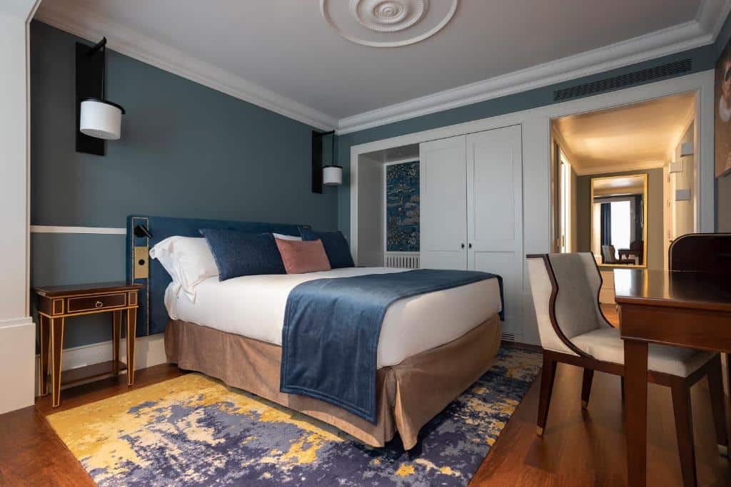 Quarto do ICON Duplo Ribeira com cama de casal do lado esquerdo, uma cômoda do lado esquerdo da cama e em frente a cama uma mesa de trabalho. Representa hotéis de luxo no Porto.