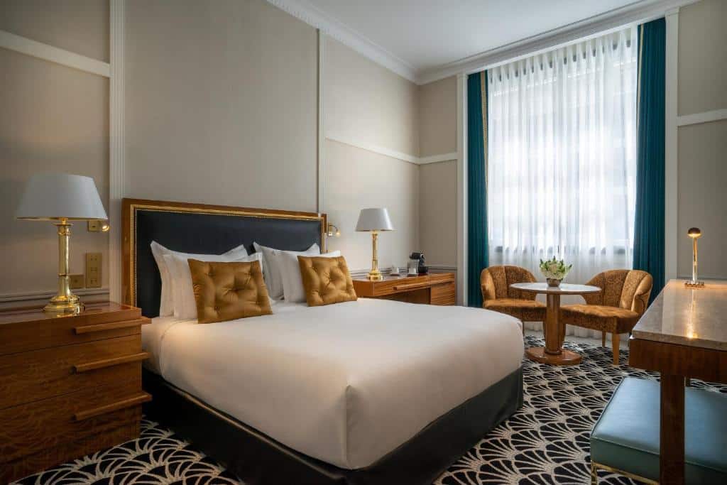 Quarto do Maison Albar Hotels Le Monumental Palace com cama de casal do lado esquerdo com duas cômodas ao lado da cama com luminária. Representa hotéis de luxo no Porto.