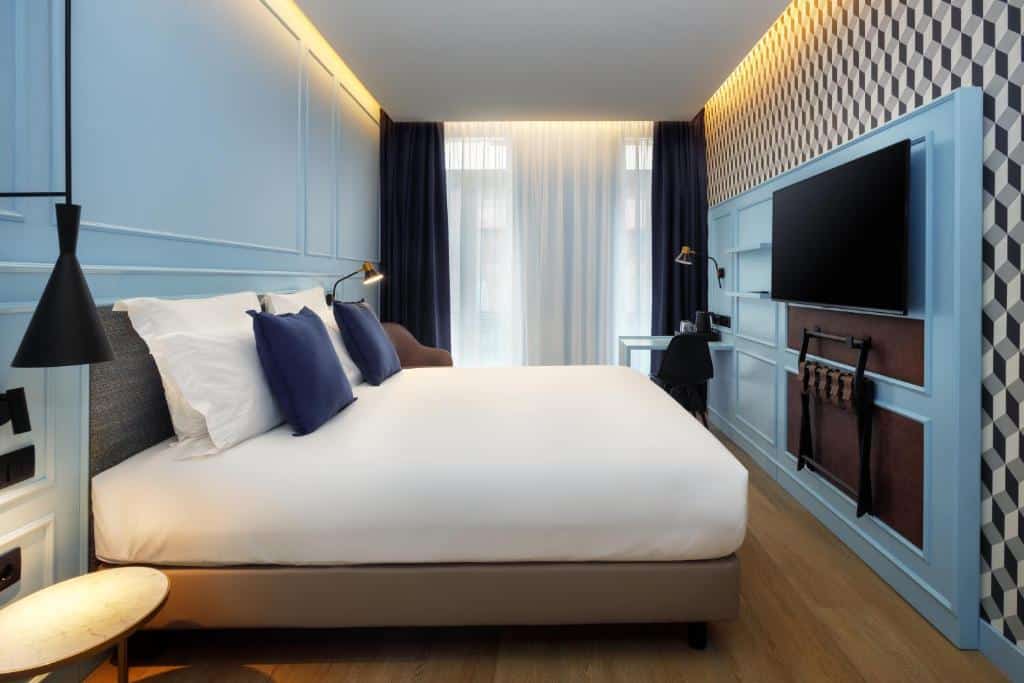 Quarto do Mercure Porto Centro Aliados com cama de casal do lado esquerdo, TV em frente a cama. Representa hotéis baratos no Porto.