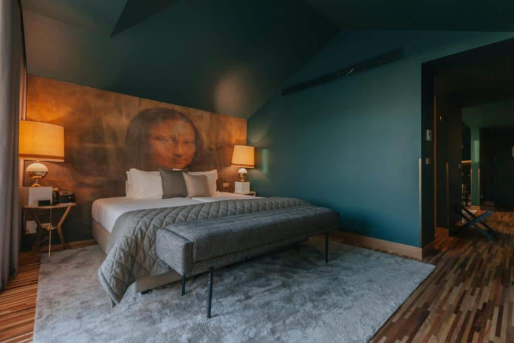 Quarto do Torel Avantgarde com cama de casal do lado esquerdo e ao lado da cama duas cômodas com luminária. Representa hotéis românticos no Porto.